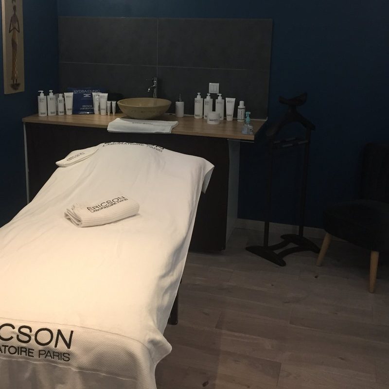 Cabine de soins visage aux murs bleu nuit, table préparée avec une serviette Ericson Laboratoire
