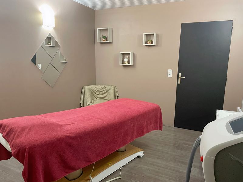 Cabine de soins aux murs taupe, table de massage au drap framboise