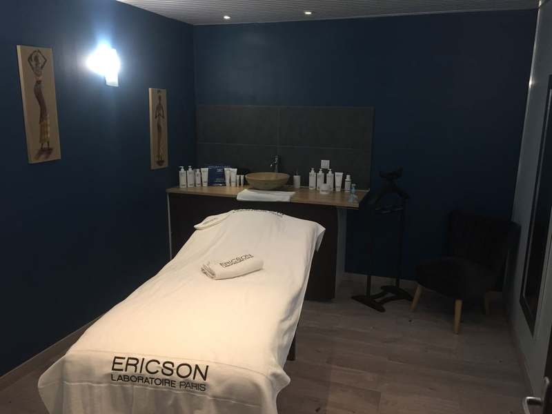 Cabine de soins visage aux murs bleu nuit, table préparée avec une serviette Ericson Laboratoire