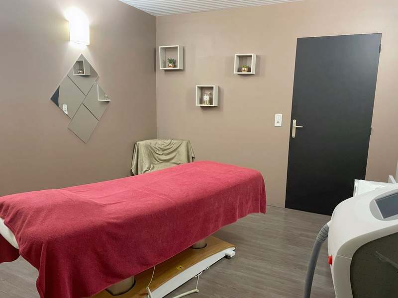 Cabine de soins aux murs taupe, table de massage au drap framboise